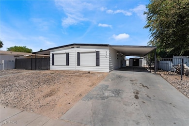View of front facade with driveway, fence, and a carport