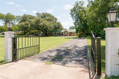 Gated entrance to a large lot with home set far ba