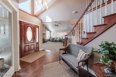 Entrance foyer with stairway, high vaulted ceiling, wood finished floors, and a chandelier