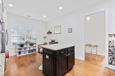Kitchen featuring light stone counters, light hardwood / wood-style floors, stainless steel fridge, and a center island