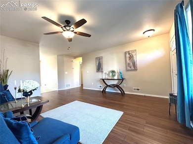 Living room featuring a ceiling fan, dark wood fin