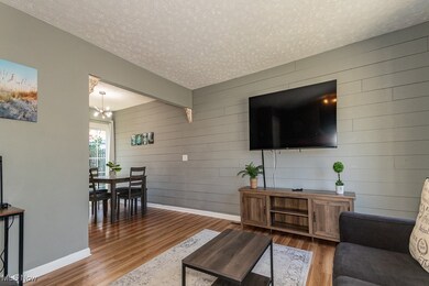 Living area featuring a textured ceiling, wood finished floors, wood walls, and a chandelier