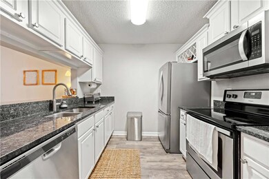 Kitchen featuring stainless steel appliances, sink, dark stone countertops, and white cabinets