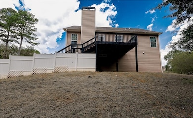 Rear view of house with a wooden deck, a chimney, and roof with shingles