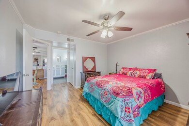 Bedroom with wood finished floors, crown molding, ceiling fan, and ensuite bath