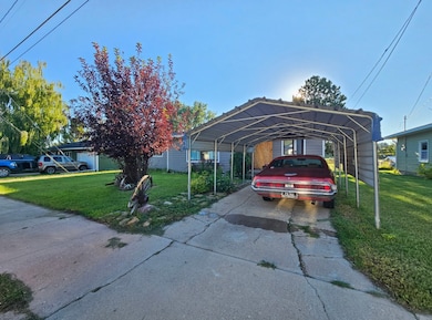 View of parking / parking lot with a carport and concrete driveway
