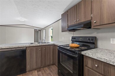Kitchen with black appliances, lofted ceiling, dark brown cabinets, a peninsula, and dark wood-type flooring