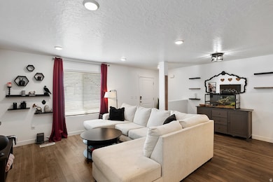 Living room featuring dark wood finished floors, a textured ceiling, and recessed lighting