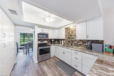 Kitchen with appliances with stainless steel finishes, a tray ceiling, ceiling fan, tasteful backsplash, and white cabinetry