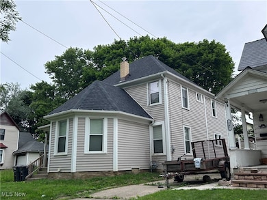 Back of house with a chimney and roof with shingles