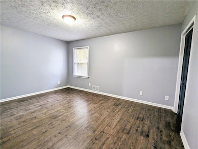 Unfurnished room featuring dark wood-style floors and a textured ceiling