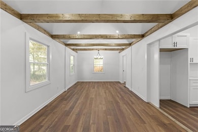 Unfurnished dining area with dark wood-style flooring, a chandelier, baseboards, and beam ceiling
