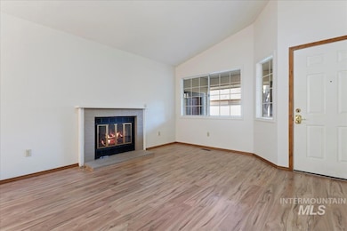 Unfurnished living room featuring lofted ceiling, light wood-type flooring, and a brick fireplace