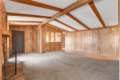 Carpeted spare room featuring vaulted ceiling with