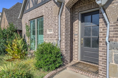 View of exterior entry with brick siding and a shingled roof