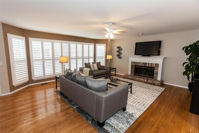 Living room boasts hardwood flooring, ceiling fan with light, bay window and gas fireplace.