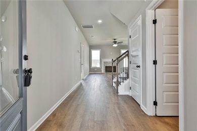 Foyer with light wood finished floors, stairway, ceiling fan, recessed lighting, and a fireplace with raised hearth
