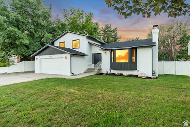Modern farmhouse style home with brick siding, a chimney, a gate, driveway, and a garage