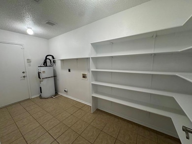 Laundry room featuring a textured ceiling, water heater, light tile patterned floors, washer hookup, and hookup for an electric dryer
