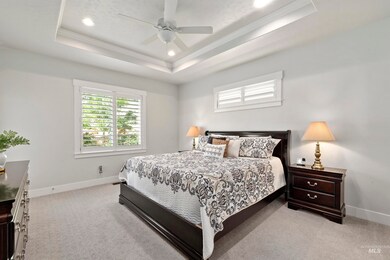 Bedroom with ornamental molding, a raised ceiling, light carpet, recessed lighting, and a ceiling fan