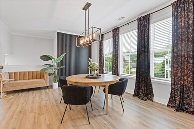 Dining area with a chandelier, ornamental molding, light wood-style flooring, and baseboards