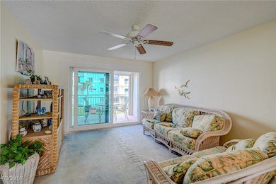 Living area with a textured ceiling, unfinished concrete floors, and ceiling fan