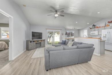 Living room featuring vaulted ceiling, light wood-style floors, a textured ceiling, ceiling fan, and recessed lighting