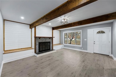 Unfurnished living room with beam ceiling, light wood-style flooring, a fireplace, a chandelier, and recessed lighting