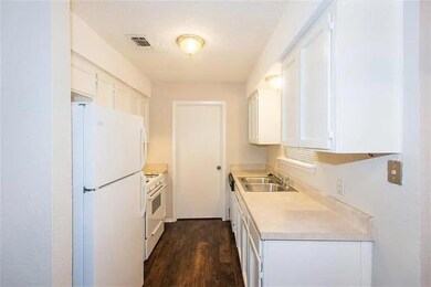 Kitchen with white appliances, a sink, light coun