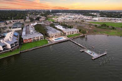 Arial view of condo, peer, pool, and lawn with sit