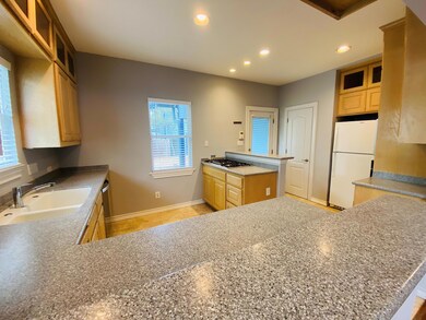 Kitchen featuring glass insert cabinets, light brown cabinetry, recessed lighting, appliances with stainless steel finishes, and a peninsula