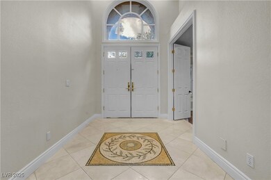 Foyer entrance with a textured wall, light tile patterned floors, and a towering ceiling