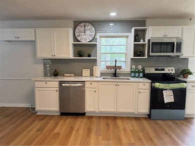Kitchen featuring a sink, open shelves, white cabi