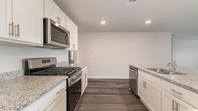 Kitchen with sink, white cabinetry, appliances wit