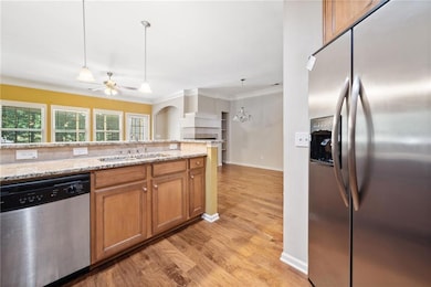 Kitchen with stainless steel appliances, a sink, light wood-style flooring, ceiling fan, and ornamental molding