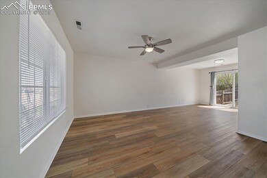 Empty room with wood finished floors, baseboards, a ceiling fan, and visible vents
