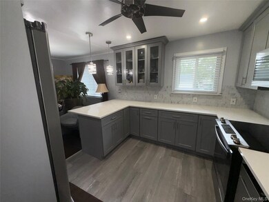 Kitchen featuring gray cabinetry, appliances with stainless steel finishes, glass insert cabinets, dark wood-style floors, and recessed lighting