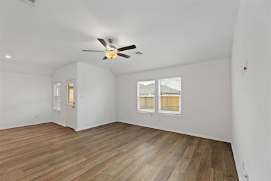 Spare room with light wood-style floors, a ceiling fan, and lofted ceiling