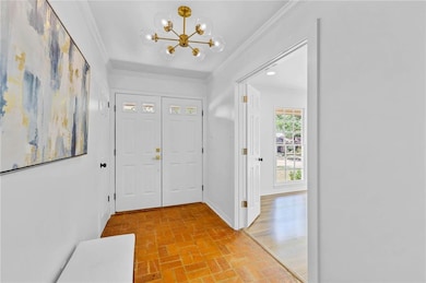 Foyer featuring brick floors, ornamental molding, and a chandelier