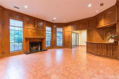 Notice the beauty of this living area with extra high ceilings, solid wood embellishments plus a custom mantle and granite hearth on this wood burning fireplace.  Amazing space for entertaining with large wet bar.  Modernize this area with your favorite paint colors or keep it cozy with its  exquisite rich wood.
