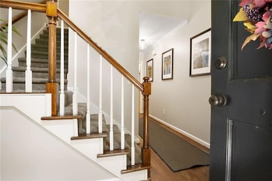Foyer with stairway, crown molding, and wood finished floors