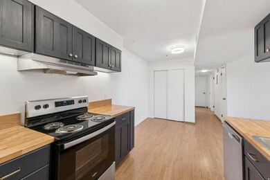 Kitchen featuring appliances with stainless steel finishes, butcher block countertops, light wood-style flooring, and under cabinet range hood
