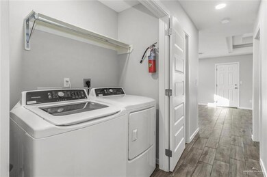 Washroom with washer and dryer, wood finished floors, baseboards, and recessed lighting