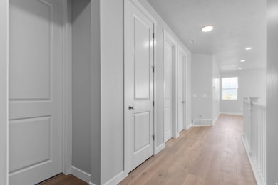 Hallway with wood finished floors, recessed lighting, and a textured ceiling