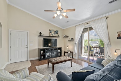 Living room with ornamental molding, lofted ceiling, ceiling fan, and wood finished floors