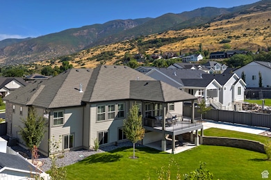 Rear view of property with a residential view, a deck with mountain view, a yard, and roof with shingles