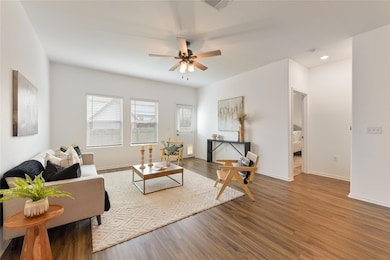 Living area featuring a ceiling fan, wood finishe