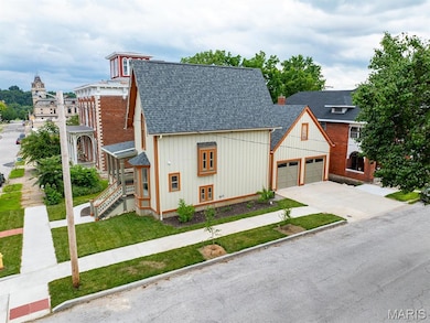 View of front facade featuring roof with shingles, a garage, a front yard, driveway, and board and batten siding