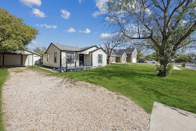 View of front facade featuring an outdoor structure, a front yard, a detached garage, and driveway