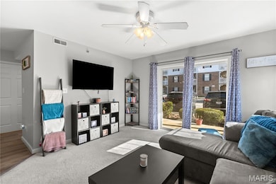 Carpeted living room featuring a ceiling fan and baseboards